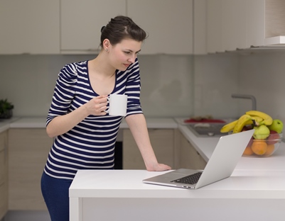 woman in kitchen looking at her laptop