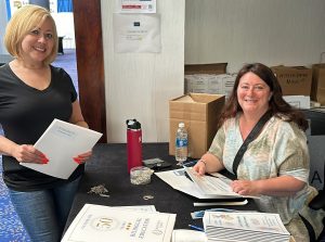 Nurka Nieves and Gina Finneran prepare presenters&#039; folders.